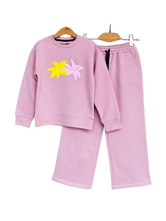 Child wearing a pink tracksuit with floral designs on a white background
