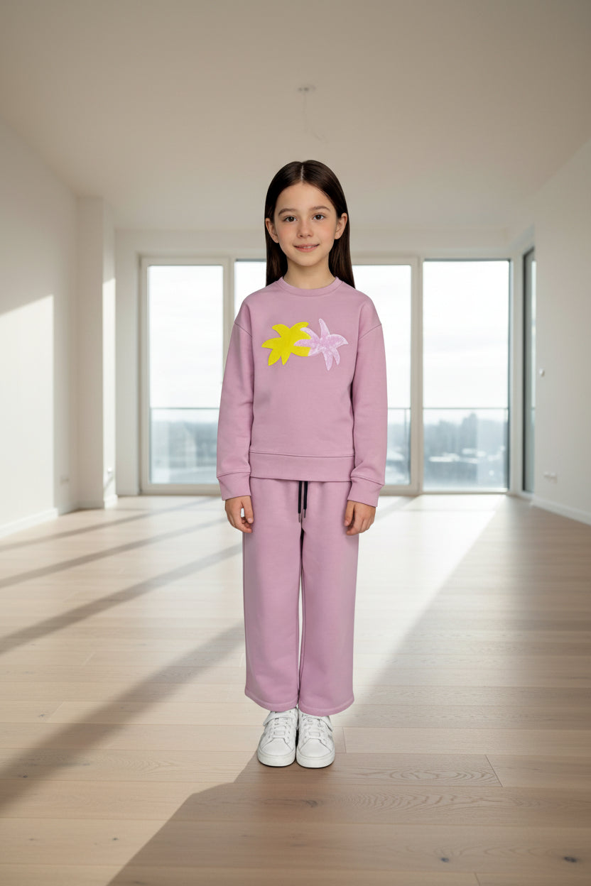 Child wearing a pink tracksuit with floral designs on a white background